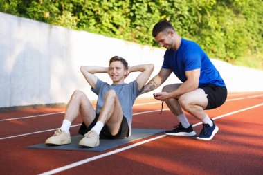 Genç adam profesyonel antrenörle dışarıda egzersiz yapıyor.