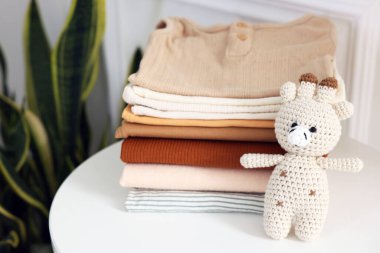 Temiz bebek kıyafetleri yığını ve beyaz masa, kapalı, yakın çekim