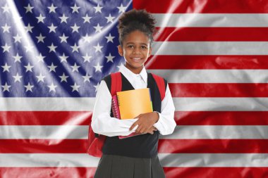 ABD bayrağına karşı sırt çantası ve defterleri olan küçük bir kız. Dil okulu