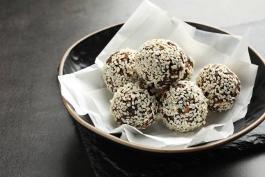 Gri masadaki kasede fındık ve susam tohumlu lezzetli çikolatalar, yakın plan.