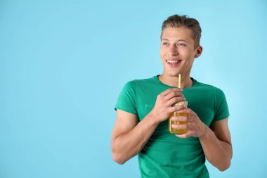 Meyve suyu ve açık mavi arka planda saman içen adam, metin için boşluk