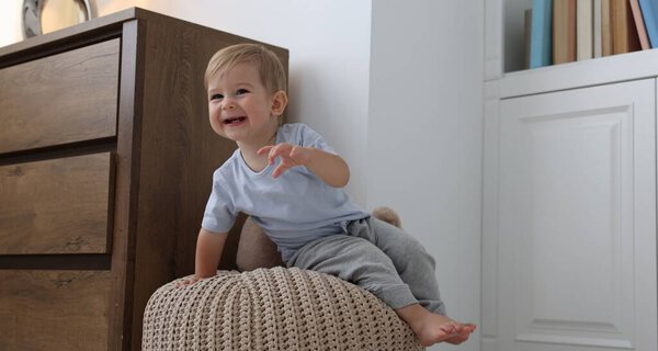 Cute little baby on pouf at home