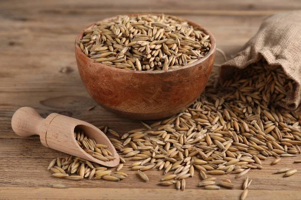 Yulaf taneleri, kepçe, kase ve çuval tahtada, yakın plan.