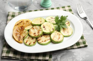 Gri masada servis edilen limonlu ve maydanozlu lezzetli kabak dilimleri.