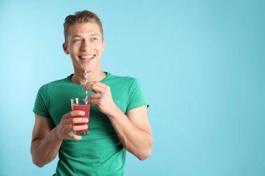 Meyve suyu ve açık mavi arka planda saman içen adam, metin için boşluk