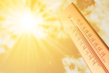 Güneşli bir günde, turuncu gökyüzüne karşı termometrede son derece yüksek sıcaklık. Şiddetli sıcak yaz havası