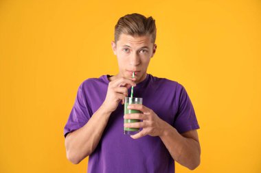 Turuncu arka planda samandan meyve suyu içen adam.