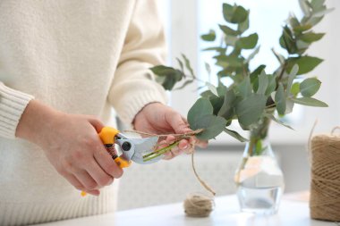 Çiçekçi çiçekçide okaliptüs dallarından güzel bir buket yapıyor, yakın plan.