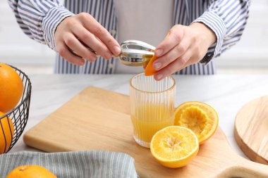 Meyve suyu. İçerideki beyaz mermer masada portakal suyu kullanan kadın, yakın plan.