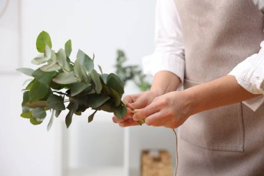 Çiçekçi, çiçekçide okaliptüs dallarından güzel bir buket yapıyor.