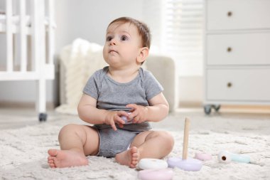 Odada oyuncak piramitle oynayan şirin bir bebek.