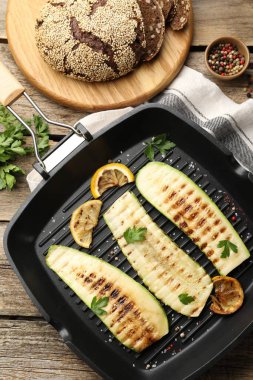 Lezzetli ızgara kabak dilimleri, baharatlar ve tavada limon, ahşap masa, düz yatış.