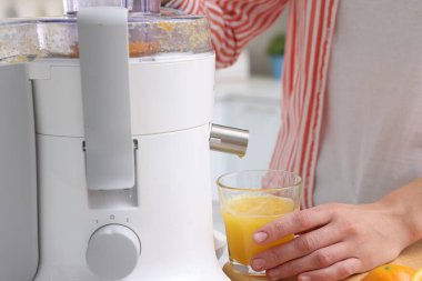 Modern meyve sıkacağıyla taze portakal suyu yapan kadın, yakın plan.