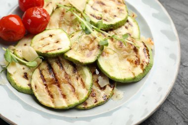 Lezzetli ızgara kabak dilimleri, domatesler ve mikro yeşiller masada, yakın plan.