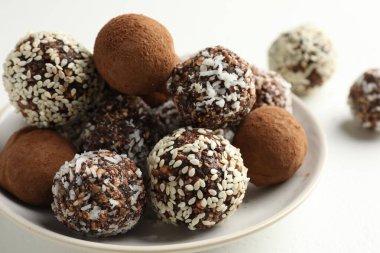 Beyaz masada kakao tozu, fındık ve susam tohumlu lezzetli çikolata şekerleri, yakın plan.