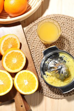 Taze sıkılmış portakal suyu, meyve suyu ve meyve sıkacağı ahşap masada, düz yerde.
