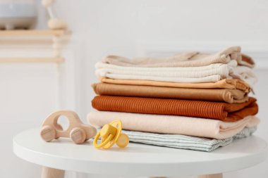 Temiz bebek kıyafetleri ve aksesuarlar beyaz masa içinde, yakın plan.