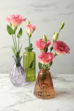 Beyaz mermer masadaki cam vazolarda güzel Eustoma çiçekleri.