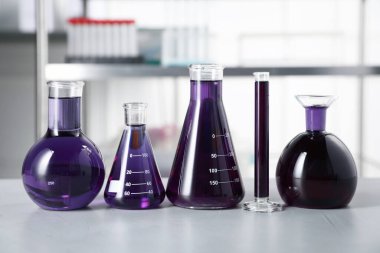 İçerideki ışık masasının üzerinde mor sıvı bulunan farklı bir laboratuvar camı.