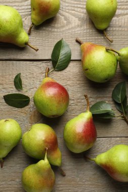 Taze armutlar ve ahşap masada yeşil yapraklar, düz uzanmış.