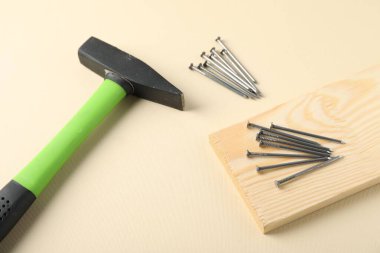 Bej arka planda metal çiviler, çekiç ve ahşap tahtalar.