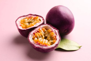 Taze tutku meyveleri ve pembe arka planda yeşil yaprak, yakın plan.