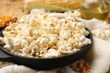 Lezzetli patlamış mısır, mısır taneleri, yağ ve havlu ahşap masada, yakın plan.