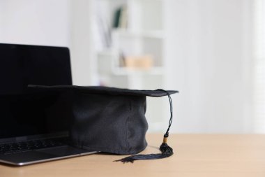 Mezuniyet şapkası ve dizüstü bilgisayar kapalı masa, yakın plan. Metin için boşluk