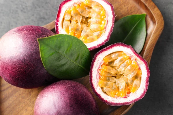 Taze tutku meyveleri ve yeşil yapraklar gri masada, üst manzara