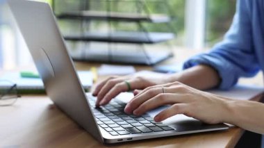 Ahşap masada dizüstü bilgisayar kullanan bir kadın, yakın plan. Ev işyeri