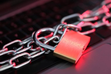 Siber güvenlik. Metal asma kilit, dizüstü bilgisayarında renk ışığı, yakın plan.