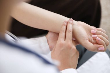 Doktor kadının nabzını kontrol ediyor. Parmakları içeride, yakın plan.