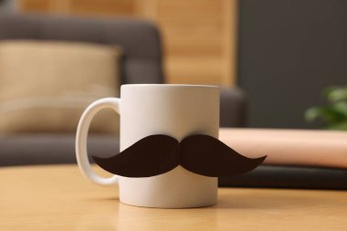 Babalar Günün kutlu olsun. Kağıt bıyıklı kupa ve kapalı masa üzerindeki kitaplar, yakın plan.