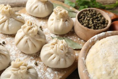 Biber, un ve defne yapraklarıyla pişirilmemiş khinkaliler (hamur köfteleri) ahşap masada, yakın plan