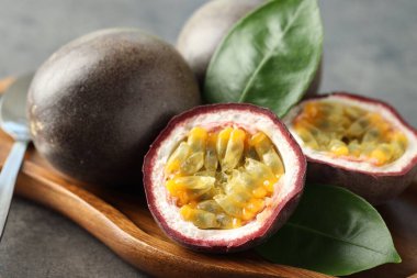 Taze tutku meyveleri ve yeşil yapraklar gri masada, yakın plan.