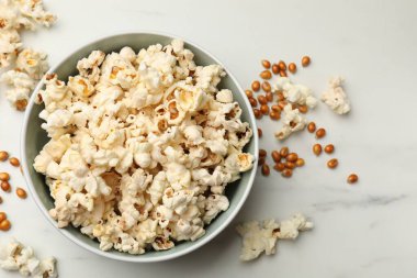 Lezzetli patlamış mısır ve mısır taneleri beyaz mermer masada, düz yerde.