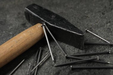 Çekiç ve metal çiviler gri masada, yakın plan.