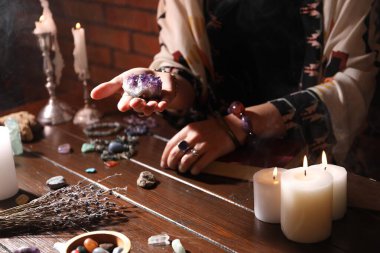Kadın ahşap masada iyileştirme taşlarıyla ayin yapıyor, yakın plan.