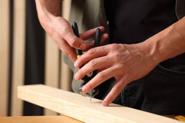 Kapalı alanda kıskacı olan tahta çiviyi söken adam, yakın plan.