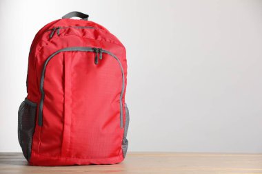 Kırmızı sırt çantası ahşap masada, arka planda. Metin için boşluk