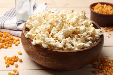 Lezzetli patlamış mısır ve mısır taneleri açık ahşap masada, yakın plan.