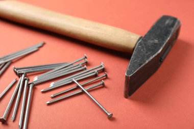 Mercan zemin üzerinde metal çiviler ve çekiç, yakın plan.