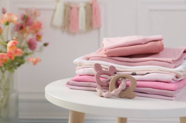 Temiz bebek kıyafetleri yığını ve beyaz masa, kapalı, yakın çekim