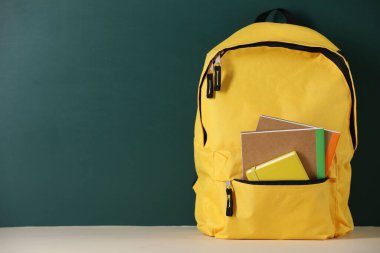 Tahtanın yanındaki masada defterli sarı sırt çantası. Metin için boşluk