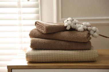 Temiz havlular ve pamuk çiçekleri evdeki ahşap çekmecelerin üzerinde, yakın plan.