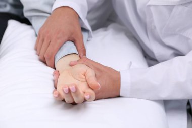 Doktor evde parmaklarıyla kadının nabzını kontrol ediyor.