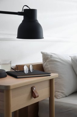 İçinde lamba, defter, bardaklar ve bardaklar olan komodin.