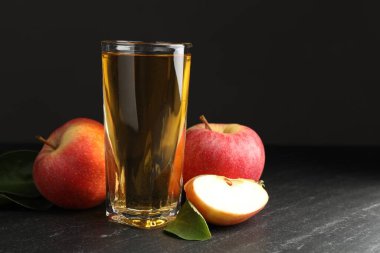 Taze elma şarabı, elma ve yeşil yapraklar siyah masada, metin için boşluk