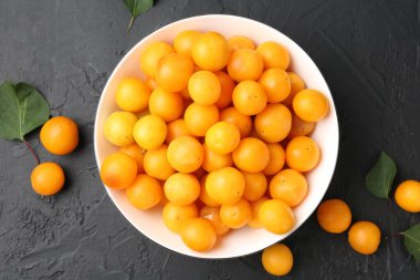 Olgun sarı kiraz erikleri ve yaprakları siyah masanın üzerinde, düz yatıyordu.