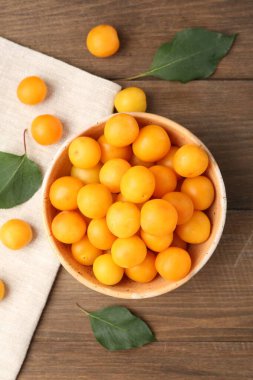 Olgun sarı kiraz erikleri ve yaprakları ahşap masada, düz yatıyordu.